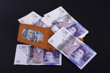 Üzerinde para olan sarı deri bir cüzdan koyu bir arka planda duruyor.