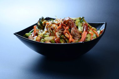 Et, sebze ve soslu sıcak salata koyu bir tabakta.