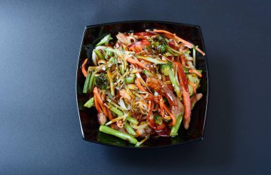 Et, sebze ve soslu sıcak salata koyu bir tabakta.