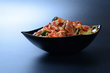 Et, sebze ve soslu sıcak salata koyu bir tabakta.