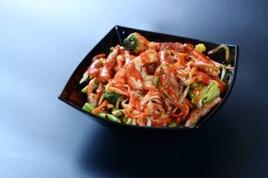 Et, sebze ve soslu sıcak salata koyu bir tabakta.