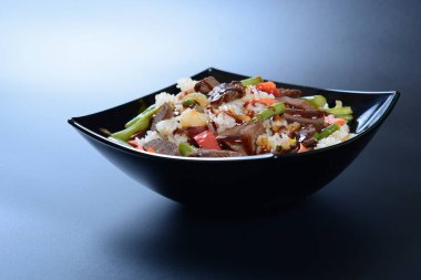 Bir tabak beyaz pirinç, yeşil sebze, baharat ve haşlanmış et.