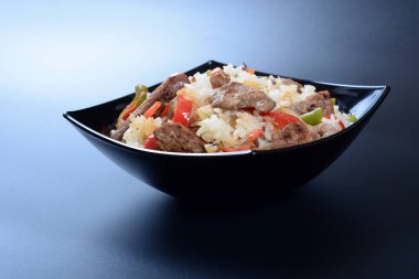 Bir tabak beyaz pirinç, yeşil sebze, baharat ve haşlanmış et.