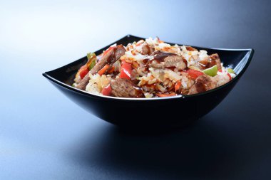 Bir tabak beyaz pirinç, yeşil sebze, baharat ve haşlanmış et.