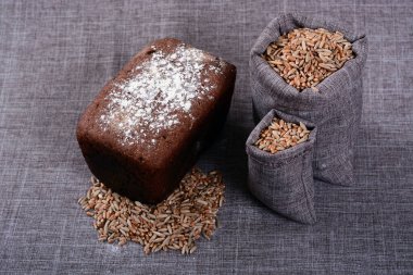 Tahıl çuvallarının yanında bir somun siyah ekmek yatıyor.