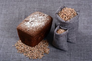 Tahıl çuvallarının yanında bir somun siyah ekmek yatıyor.