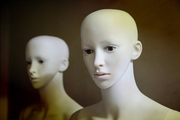 White scary mannequins stand and look at each other with their eyes