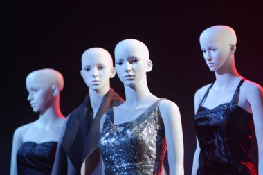 Beyaz kadın mankenler dikilip birbirlerine gözleriyle bakıyorlar.