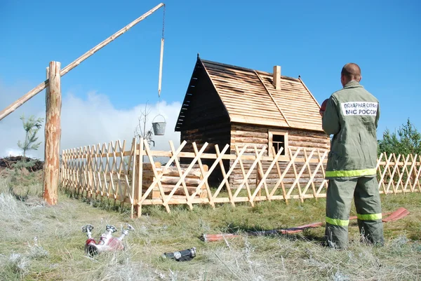 Bombero se encuentra cerca de la casa quemada y bien en Siberia — Foto de Stock