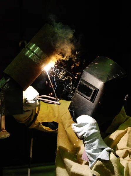 Soldador trabalhador vai soldar estrutura de metal em um fundo escuro — Fotografia de Stock