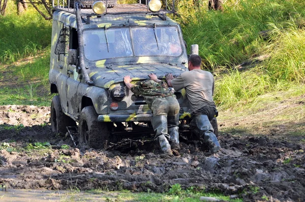 Two people pull out a stuck vehicle