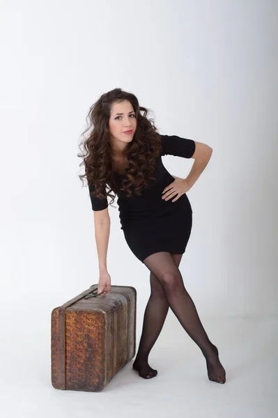 Beyaz arka plan üzerinde antik bavul ile esmer kız duruyor