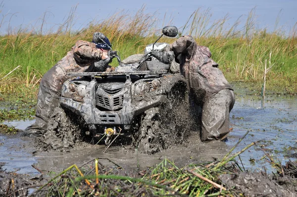 Two men in dirty clothes push a car stuck