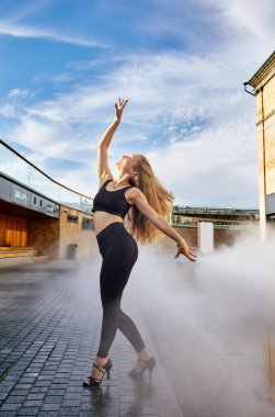 Şehir caddesinde poz veren uzun sarı saçlı güzel bir kadın dansçı. Kadın dans doğaçlaması - Latin dansı, tango, çağdaş ve bachata