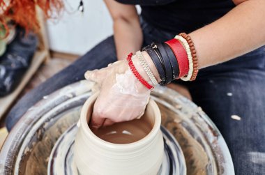 Kadının elleri kil kalıbı çıkarıyor. Potter çömlek atölyesinde seramik demlik yapıyor.