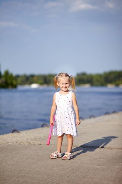Beyaz elbiseli sevimli çocuk dışarıda poz veriyor. Kız eğleniyor. Parktaki küçük kız. Yaz ya da bahar tatili