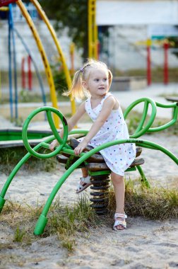 Parktaki çocuk parkında oynayan mutlu gülümseyen kız çocuğu. Kız eğleniyor. Yaz ya da bahar tatili