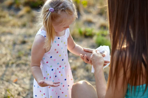 Mom wipes her daughters palm with a damp napkin. Mom cares for her little daughter. Corona Virus pandemic protection by washing hands