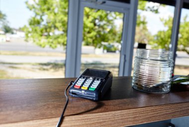 Kredi kartı ödeme terminali kahve dükkanının masasında. Temassız ödeme aygıtı, kart makinesinin yakın plan görüntüsü