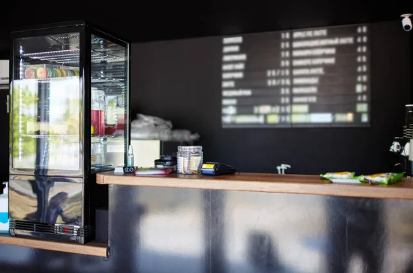 Kafenin içinde. Vitrinin bulanık görüntüsü, tezgah ve adı sıcak ve soğuk içeceklerin olduğu ahşap pano, fiyatlar.