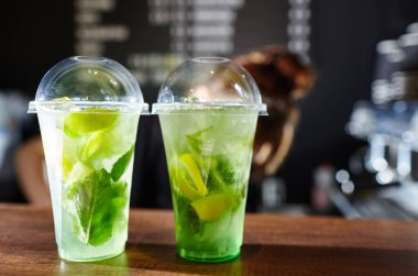 Barmen mojito kokteyli yapıyor. Barmenliğin işleyişi. Buzlu meyve ve bitki süslemeli taze kokteyl içeceği. Bulanık resim, seçici odak