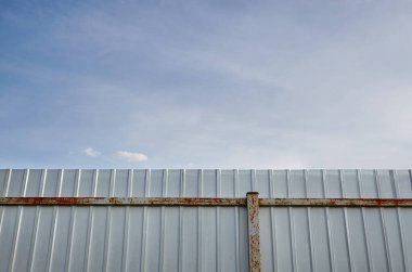 Demir paslı çit. Beyaz kıvrımlı metal veya çinko desen yüzeyi veya dikey arkaplanda çeliği galvanize et.