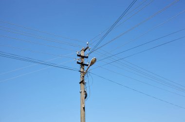 Eski elektrik direğinin bir yaz günü yakınlaşması. Açık mavi gökyüzüne karşı elektrik kablolarıyla elektrik hattı direği