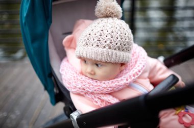Sonbahar parkında bebek arabasında yürüyüş. Mavi sandalyede oturan, sıcak giysili sevimli küçük kız. Bebek arabasındaki çocuk