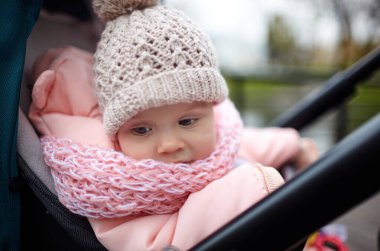 Sonbahar parkında bebek arabasında yürüyüş. Mavi sandalyede oturan, sıcak giysili sevimli küçük kız. Bebek arabasındaki çocuk