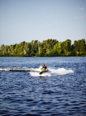 Güçlü adam suyun üstündeki jetski 'ye atlıyor. Yaz tatilinde jet ski kullanan bir adam.