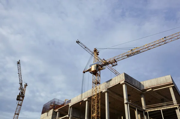 Tower cranes building a house. Concrete building under construction. Construction site.