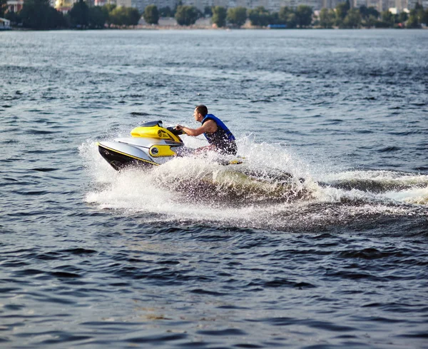 Güçlü adam suyun üstündeki jetski 'ye atlıyor. Yaz tatilinde jet ski kullanan bir adam.