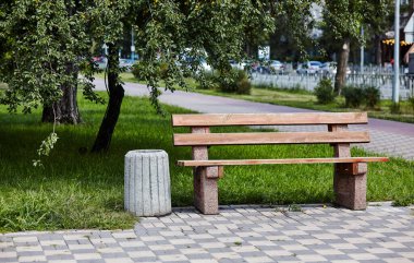 Şehir parkındaki ahşap bank. Güneşli bir yaz sabahında yeşil alanda boş bir bank.