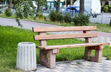 Şehir parkındaki ahşap bank. Güneşli bir yaz sabahında yeşil alanda boş bir bank.