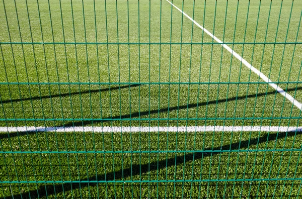 芝生のフィールドは 緑のフェンスメッシュの後ろにサッカーをプレイする 緑の芝生のサッカー場の閉鎖 — ストック写真