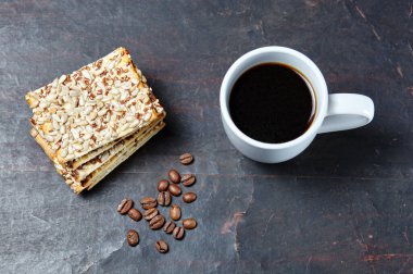 Kahveli beyaz fincan, kahve çekirdekleri ve ahşap arka planda çıtır çıtır çıtır çıtır çıtır çıtır ekmek, yakın plan. Lezzetli kahvaltı, sabah rutin konsept, üst manzara