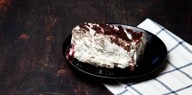 Tabakta bir dilim lezzetli çikolatalı pasta var. Ahşap arka planda lezzetli bir tatlı, yakın planda.