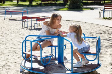 Anne ve kızı yaz kenti parkında oyun oynuyorlar. Çocukluk, eğlence ve insan konsepti. Mutlu aile istirahatı ve iyi vakit geçirmek.