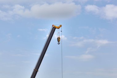 Mavi arka planda yüzen bir kargo vincinin ayrıntıları. İnşaat, ulaşım, ereksiyon vb gibi birçok sektörde ağır kaldırma ve nesneleri hareket ettirmek için kullanılan taşınabilir vinç parçası