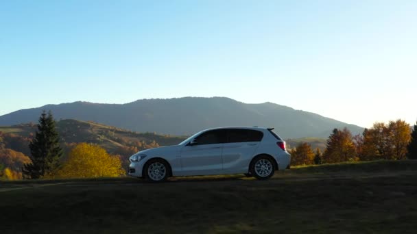 Top cinematic aerial view of the sport car which drives up the hill in the Carpathian Mountains. Ukraine. Ukrainian wild nature. Autumn season. Traveling around country. Car trip with friends. Active lifestyle holidays. Amazing autumn colors