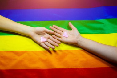 Lgbt topluluğunun renkli bayrağı. Gökkuşağı arka planında iki kadın eli. Lezbiyen ve gey sorunları. Evliliğin homoseksüel yönelimli çiftler için yasallaştırılması. Cinsiyet eşitliği.
