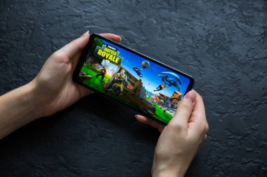 LVIV, UKRAINE - 25 Ekim 2020: Modern akıllı telefonda mobil oyun Battle Royal Fortnite oynamak.