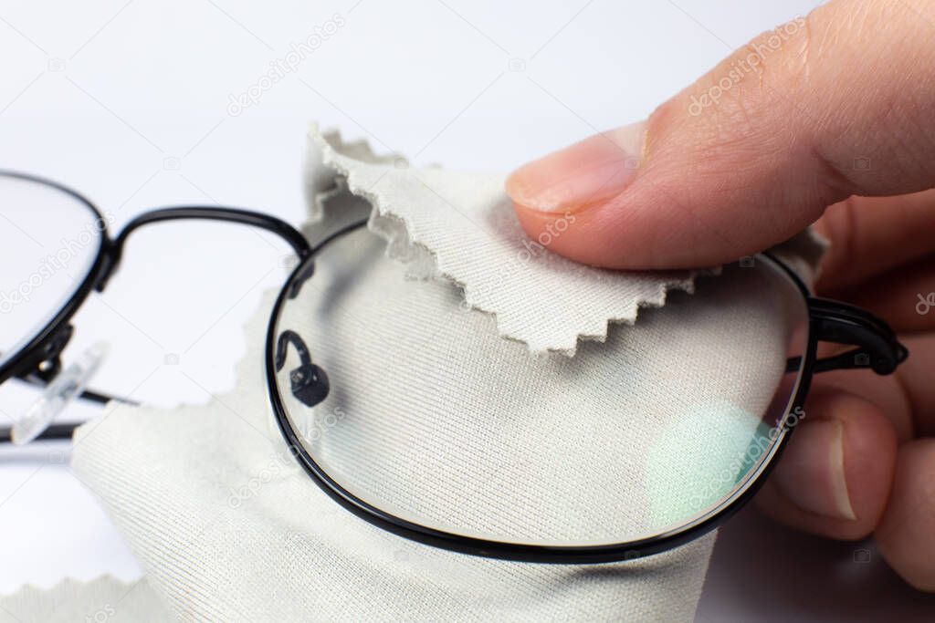 Woman cleaning reading glasses with cloth. Close up photo.