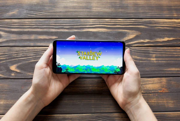 LVIV, UKRAINE - 25 Ekim 2020: Modern akıllı telefonda mobil oyun Stardew Valley oynamak.