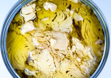 Beyaz arka planda yağlı konserve ton balığı eti. Kutu açıldı, resmi kapat..