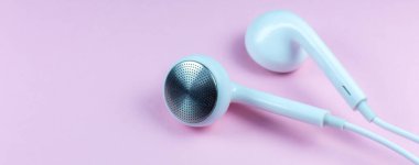 Pembe arka planda beyaz kulaklıklar var. Modern müzik konsepti. Ses teknolojisi. Fotoğrafı kapat..
