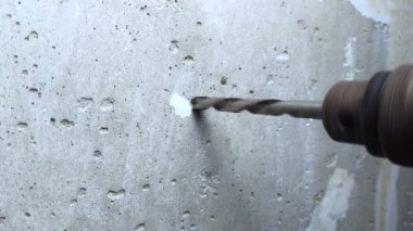 İşçi beton duvarda delik açıyor. İçeride tamirat işe yarar. Dairede tadilat var. Görüntüyü kapat.