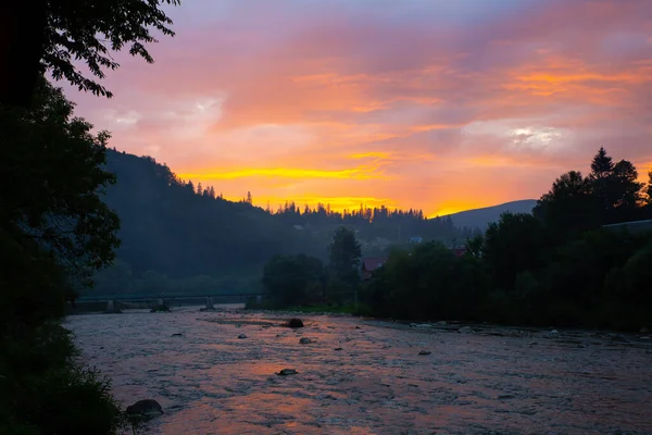 Beautiful sunset in mountains. Purple sky colours and clouds. Amazing reflection in river. Travelling concept. Perfect evening nature.