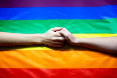 Lgbt topluluğunun renkli bayrağı. Gökkuşağı arka planında iki kadın eli. Lezbiyen ve gey sorunları. Eşcinsel yönelimli çiftler için evliliğin yasallaştırılması.