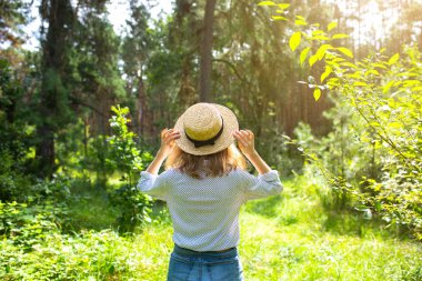 Hasır şapkalı hippi kız ormanda dikiliyor. Seyahat tutkusu konsepti. Seyahat fikirleri. Doğada güzel bir kadın. Yaz titreşimleri.
